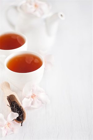 simsearch:400-05153477,k - Oolong tea in a scoop, cups and teapot with light rose rhododendron flowers. Copy space background. Photographie de stock - Aubaine LD & Abonnement, Code: 400-07574714