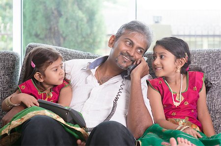Husband making a phone call to wife while taking care of children at home. Asian Indian family at home. Stock Photo - Budget Royalty-Free & Subscription, Code: 400-07574727