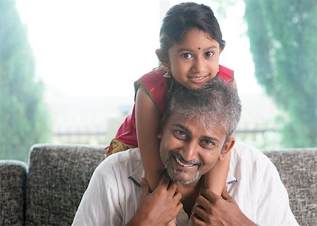 Happy Indian family at home. Asian father piggyback her daughter, sitting on sofa. Parent and child indoor lifestyle. Stock Photo - Budget Royalty-Free & Subscription, Code: 400-07574721