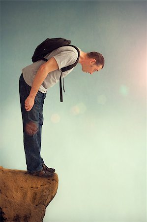 man looking down from a rocky ledge with backpack Stock Photo - Budget Royalty-Free & Subscription, Code: 400-07576555