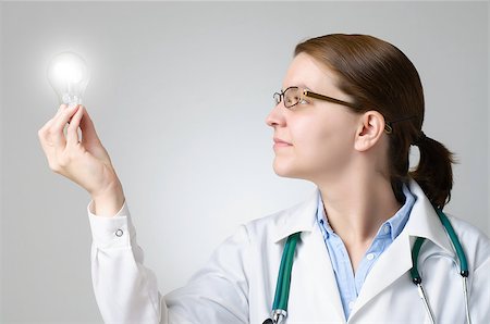 Female doctor holding and looking a glowing light bulb Stock Photo - Budget Royalty-Free & Subscription, Code: 400-07572313