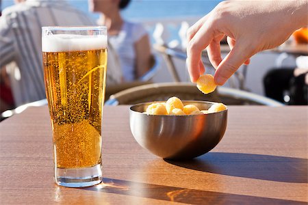 photojope (artist) - A hand picking snacks from a bowl and a beer in a table of a terrace near the sea in a sunny summer day. Photographie de stock - Aubaine LD & Abonnement, Code: 400-07573354