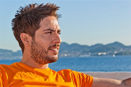 photojope (artist) - A young disheveled lifeguard with orange t-shirt in the beach looking right. Photographie de stock - Aubaine LD & Abonnement, Code: 400-07573357