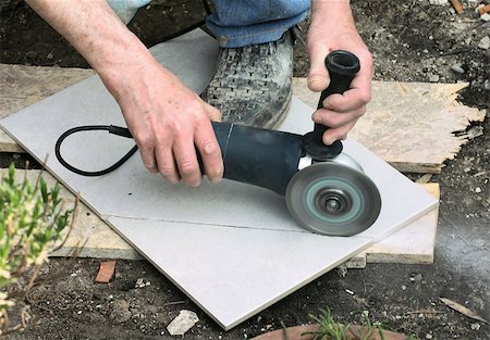 Craftsman is cutting a floor tile with a portable angle grinder Fotografie stock - Microstock e Abbonamento, Codice: 400-07573368