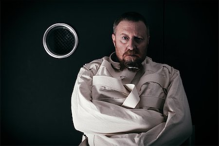 Photo of an insane man in his forties wearing a straitjacket standing in a cell of an asylum with the light from the hallway streaming in. Stock Photo - Budget Royalty-Free & Subscription, Code: 400-07580794
