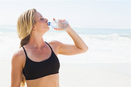 simsearch:400-07581190,k - Fit blonde drinking water on the beach on a sunny day Photographie de stock - Aubaine LD & Abonnement, Code: 400-07581210