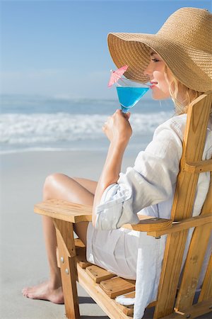 Smiling blonde relaxing in deck chair by the sea sipping cocktail on a sunny day Stock Photo - Budget Royalty-Free & Subscription, Code: 400-07581648