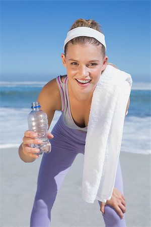 simsearch:400-07581190,k - Sporty smiling blonde standing on the beach with towel and bottle on a sunny day Photographie de stock - Aubaine LD & Abonnement, Code: 400-07582429