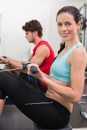 simsearch:400-07725772,k - Smiling brunette working out on the rowing machine at the gym Photographie de stock - Aubaine LD & Abonnement, Code: 400-07583210