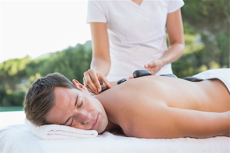 Handsome man getting a hot stone massage poolside outside at the spa Stock Photo - Budget Royalty-Free & Subscription, Code: 400-07583336