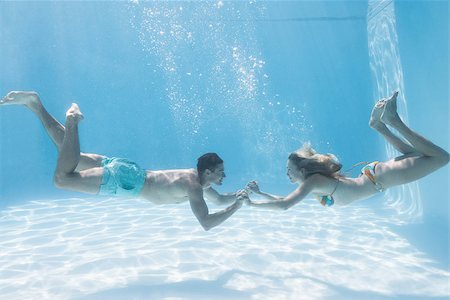 simsearch:400-07583483,k - Cute couple holding hands underwater in the swimming pool on their holidays Foto de stock - Royalty-Free Super Valor e Assinatura, Número: 400-07583455