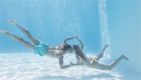 simsearch:400-07583483,k - Cute couple holding hands underwater in the swimming pool on their holidays Foto de stock - Royalty-Free Super Valor e Assinatura, Número: 400-07583456