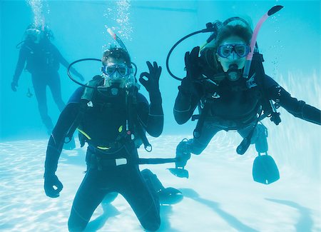 simsearch:400-07583483,k - Friends on scuba training submerged in swimming pool two looking to camera on their holidays Foto de stock - Royalty-Free Super Valor e Assinatura, Número: 400-07583495