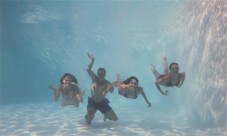 simsearch:400-07583483,k - Smiling friends looking at camera underwater in swimming pool on their holidays Foto de stock - Royalty-Free Super Valor e Assinatura, Número: 400-07583616