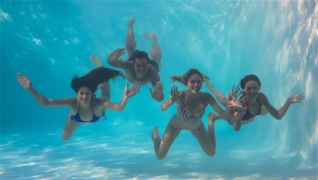 simsearch:400-07583483,k - Smiling friends looking at camera underwater in swimming pool on their holidays Foto de stock - Royalty-Free Super Valor e Assinatura, Número: 400-07583618