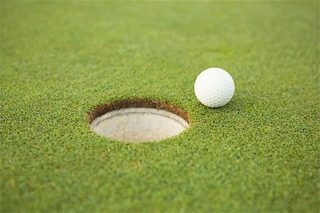 Golf ball at the edge of the hole on a sunny day at the golf course Stock Photo - Budget Royalty-Free & Subscription, Code: 400-07583622