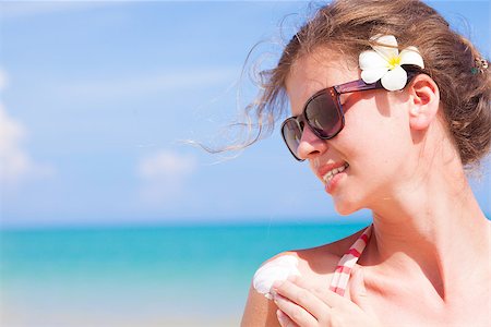 sun care - Young woman in sunglasses putting sun cream on shoulder Foto de stock - Super Valor sin royalties y Suscripción, Código: 400-07614324