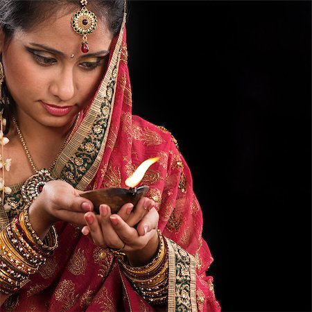 Beautiful Indian woman hands holding diya oil lamp, celebrating diwali festive of lights, traditional sari prayer isolated on black background with copy space on side. Stock Photo - Budget Royalty-Free & Subscription, Code: 400-07616580