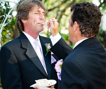 One groom feeds another wedding cake at their gay marriage ceremony. Foto de stock - Super Valor sin royalties y Suscripción, Código: 400-07624437