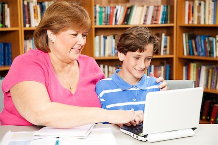 Mom or teacher working with a school boy on the computer in the library. Stock Photo - Budget Royalty-Free & Subscription, Code: 400-07624452