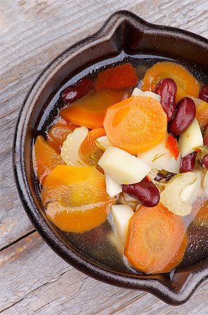 simsearch:400-07625359,k - Vegetable Stew with Carrot, Potato, Red Bean, Celery, Greens and Bouillon in Black Pottery closeup on Wooden background. Top View Photographie de stock - Aubaine LD & Abonnement, Code: 400-07625357