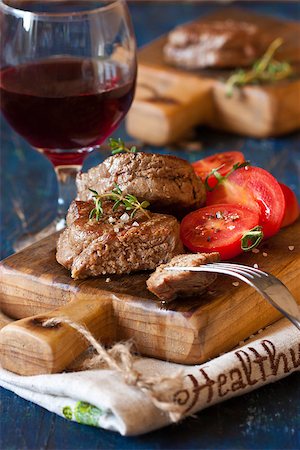 simsearch:400-08495308,k - Juicy beef steak with tomato salad served on an old wooden cutting board. Stockbilder - Microstock & Abonnement, Bildnummer: 400-07626107