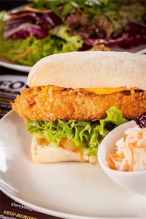 snacks and salads recipes - Closeup of a tasty burger with a golden crispy crumbed chicken breast topped with melted cheese and fresh curly lettuce on a white crusty roll Stock Photo - Budget Royalty-Free & Subscription, Code: 400-07629940