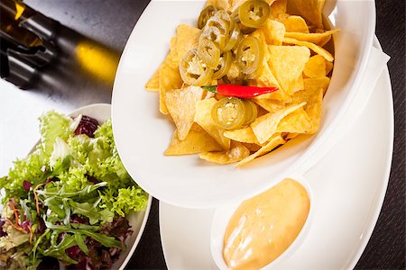 simsearch:400-07993733,k - Bowl of crisp golden corn nachos with cheese sauce or dip and olives served as a starter or appetizer to a meal Photographie de stock - Aubaine LD & Abonnement, Code: 400-07629986