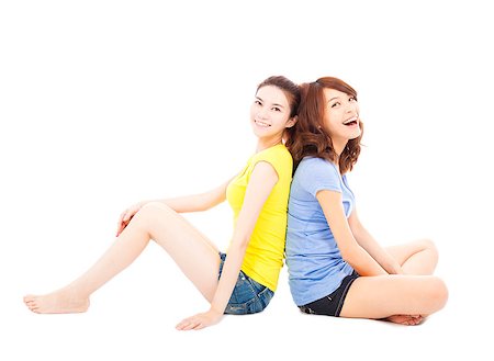 sister back to back - two smiling  young woman sitting and back to back Stock Photo - Budget Royalty-Free & Subscription, Code: 400-07620779