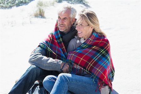 Happy couple wrapped up in blanket sitting on the beach on a bright but cool day Photographie de stock - Aubaine LD & Abonnement, Code: 400-07622742