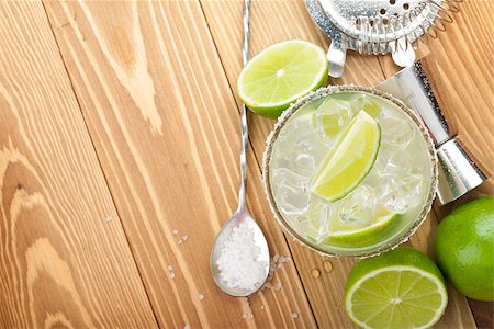 Classic margarita cocktail with salty rim on wooden table with limes and drink utensils Photographie de stock - Aubaine LD & Abonnement, Code: 400-07623860