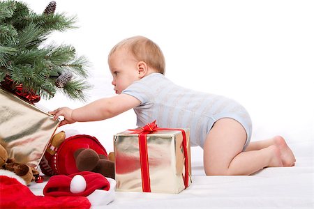 Baby boy reaching for Christmas gifts. Studio shoot on white background. Stock Photo - Budget Royalty-Free & Subscription, Code: 400-07634321