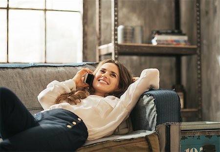 simsearch:400-08054488,k - Happy young woman laying on sofa and talking cell phone in loft apartment Stock Photo - Budget Royalty-Free & Subscription, Code: 400-07632596