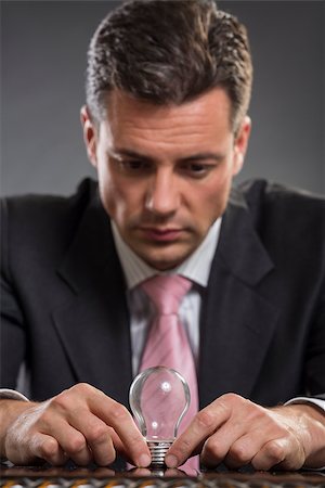 simsearch:400-06565728,k - Handsome elegant businessman thinking of smart business solution while holding a light bulb with both his hands. Foto de stock - Super Valor sin royalties y Suscripción, Código: 400-07656594