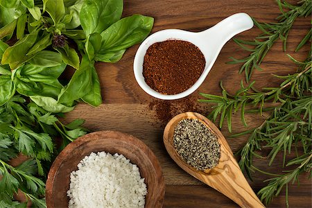 simsearch:400-06088770,k - Fun with food, wooden bowl filled with sea salt, fresh basil and parsley on the left, fresh rosemary on the right. White porcelain bowl filled with chili powder and wooden spoon filled with black pepper center.  This is shot on a wood table. Stock Photo - Budget Royalty-Free & Subscription, Code: 400-07658110