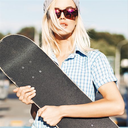 Close-up of beautiful  blond girl in beanie hat and leopard sunglasses who hugs skateboard on sunny day in the street Stock Photo - Budget Royalty-Free & Subscription, Code: 400-07659119