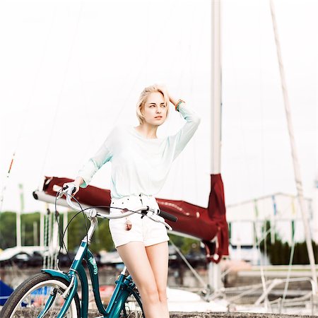 pretty tall blonde girl in short white shorts, transparent top with cruiser bike adjusts her hair at sea pier against yachts Stock Photo - Budget Royalty-Free & Subscription, Code: 400-07659146