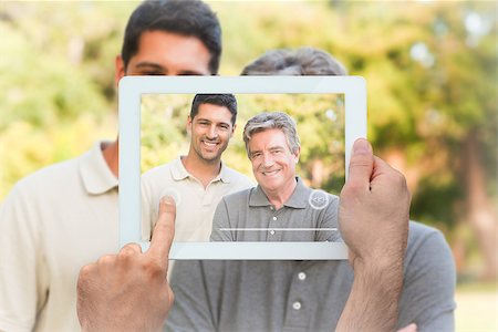 simsearch:400-07664794,k - Hand holding tablet pc showing father with his son looking at the camera Stock Photo - Budget Royalty-Free & Subscription, Code: 400-07664002