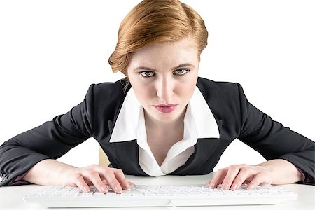 simsearch:400-07778671,k - Redhead businesswoman sitting at desk typing on white background Fotografie stock - Microstock e Abbonamento, Codice: 400-07664197