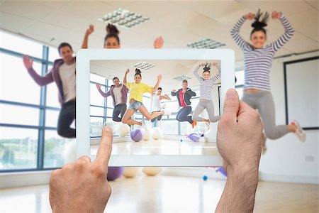 simsearch:400-07664794,k - Hand holding tablet pc showing fit people jumping in bright exercise room Stock Photo - Budget Royalty-Free & Subscription, Code: 400-07664793