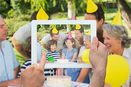 simsearch:400-07664794,k - Hand holding tablet pc showing extended family wearing party hats at birthday celebration in park Stock Photo - Budget Royalty-Free & Subscription, Code: 400-07664802