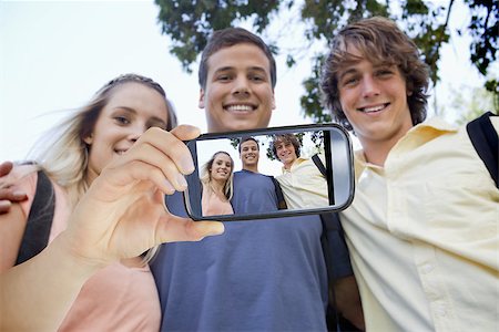 Hand holding smartphone showing low angleshot of three students shoulder to shoulder Stock Photo - Budget Royalty-Free & Subscription, Code: 400-07664815