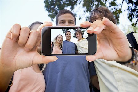 Hand holding smartphone showing low angleshot of three students shoulder to shoulder Stock Photo - Budget Royalty-Free & Subscription, Code: 400-07664823