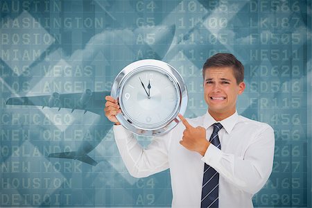 futuristic clock - Anxious businessman holding and showing a clock against airport departures board for america Stock Photo - Budget Royalty-Free & Subscription, Code: 400-07665631