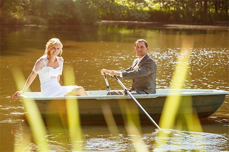 rowing together - beautiful young wedding couple, blonde bride with flower and her groom just married on small boat at pond with evening sun Stock Photo - Budget Royalty-Free & Subscription, Code: 400-07666933