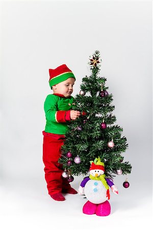 decorating small xmas tree - Baby boy dressed as Santa's Helper decorating  Christmas tree, hanging ornaments. White background. Stock Photo - Budget Royalty-Free & Subscription, Code: 400-07668641