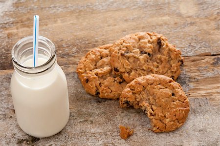stockarch (artist) - Small glass bottle of fresh creamy farm milk with a straw alongside half eaten crunchy cookies on a rustic wooden surface, high angle view Stock Photo - Budget Royalty-Free & Subscription, Code: 400-07660635