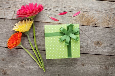 simsearch:400-07662543,k - Three colorful gerbera flowers with gift box on wooden table Stock Photo - Budget Royalty-Free & Subscription, Code: 400-07662544