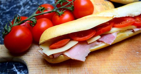 sandwich rustic table - delicious baguette sandwiches filled with thinly sliced ham or salami and fresh green lettuce or basil and tomatoes arranged in an wooden table Foto de stock - Super Valor sin royalties y Suscripción, Código: 400-07662791