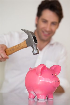 Casual businessman breaking piggy bank with hammer in his office Stock Photo - Budget Royalty-Free & Subscription, Code: 400-07662877